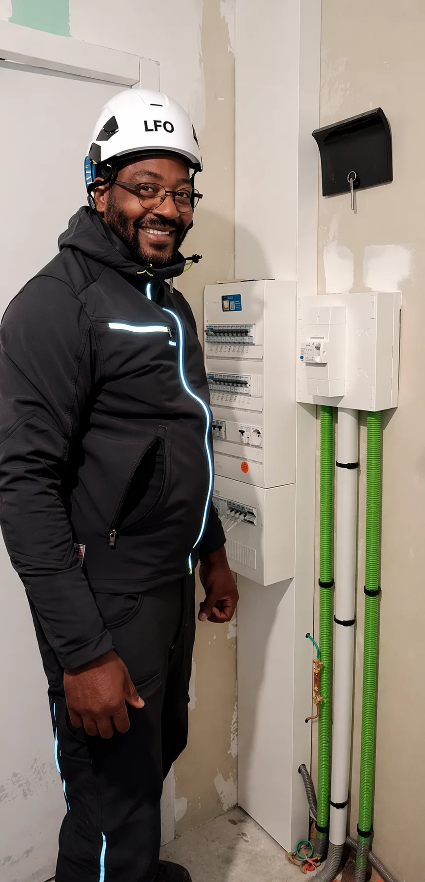 Anicet Awoa, technicien LFO, devant un tableau électrique avec installation fibre